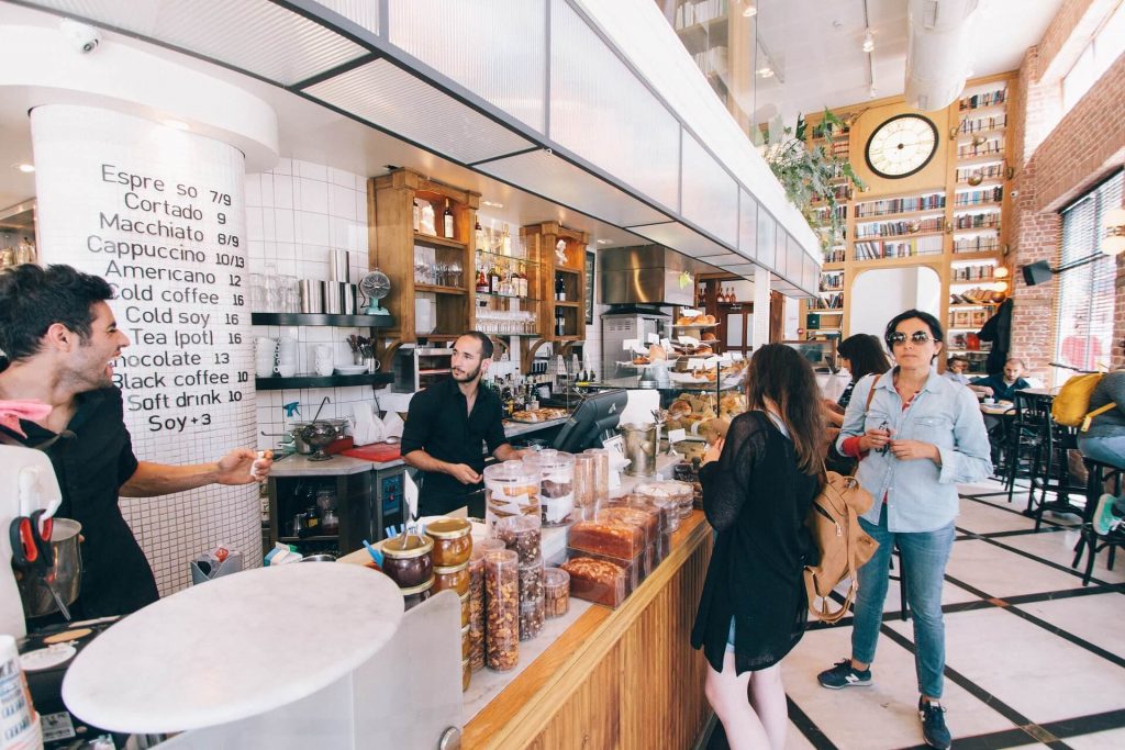 Customer service agent heling two customers in a caffe