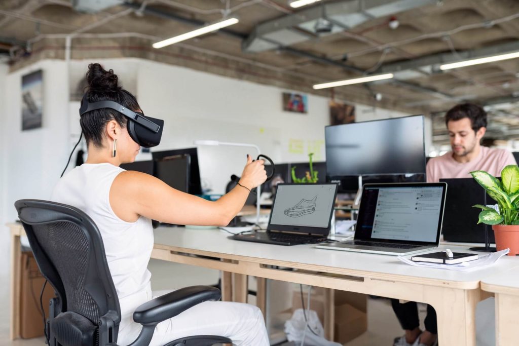 A woman in white tank top using black laptop computer with vr to improve customer experience